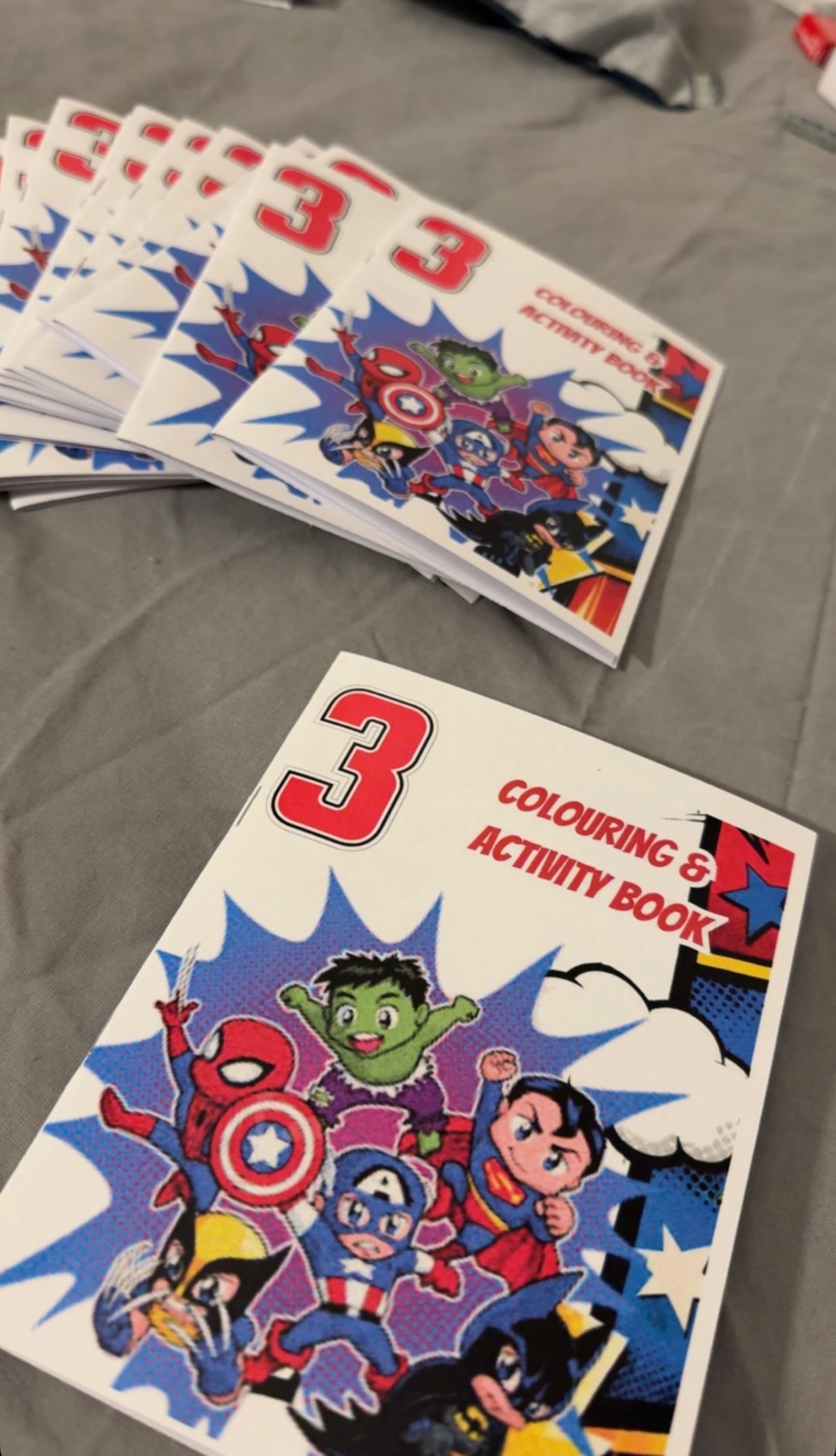 A stack of personalised superhero-themed colouring and activity books